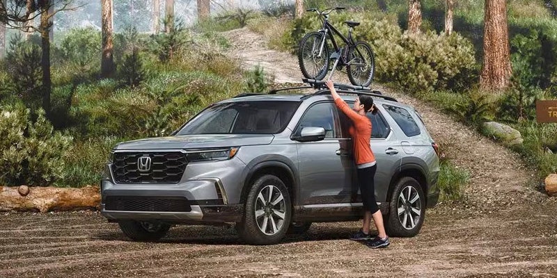 A cyclist putting their bike in the rack on top of a 2024 Honda Pilot near Bishop, CA 